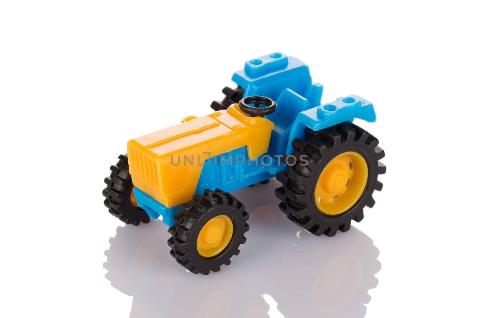 Small plastic tractor toy isolated on white background close up.