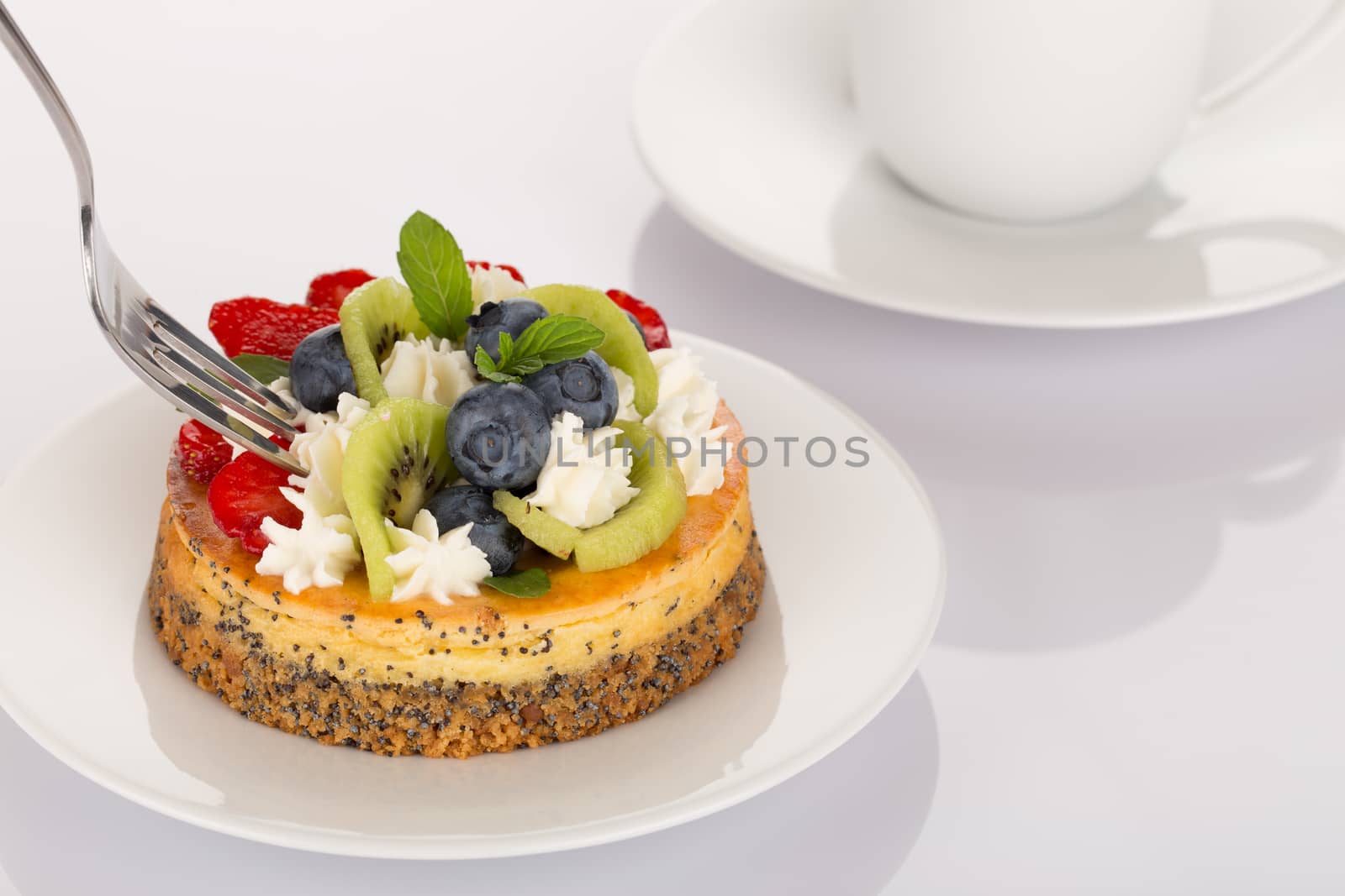 Cheese-cake with strawberries, blueberries, kiwi and cream on white plate.