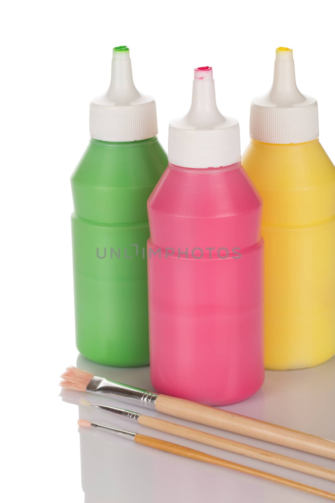 Bottles of paint and pencils isolated on white background close up.