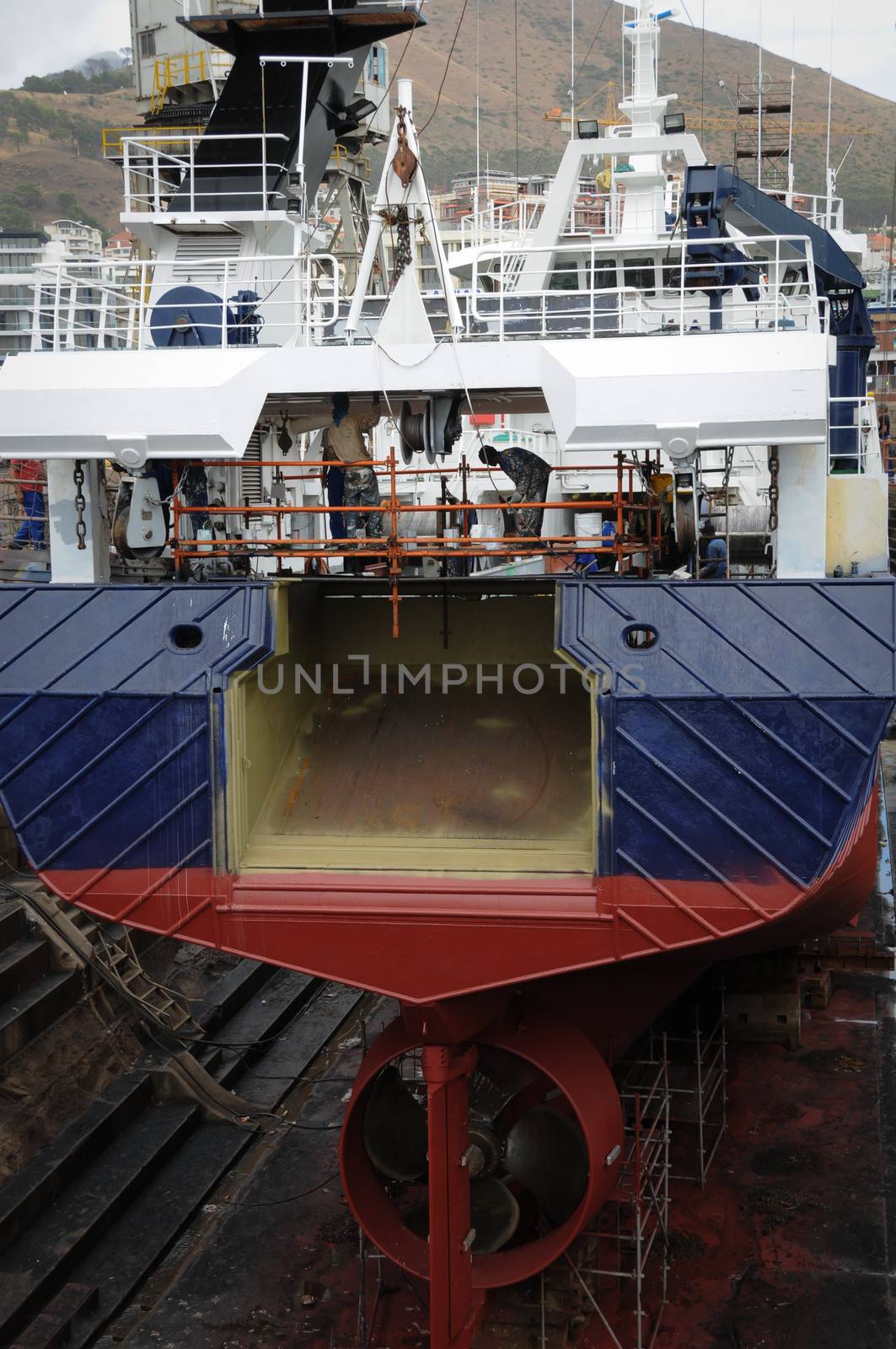 Ship in dry dock for repairing and painting. View over the stern and screw propeller. 