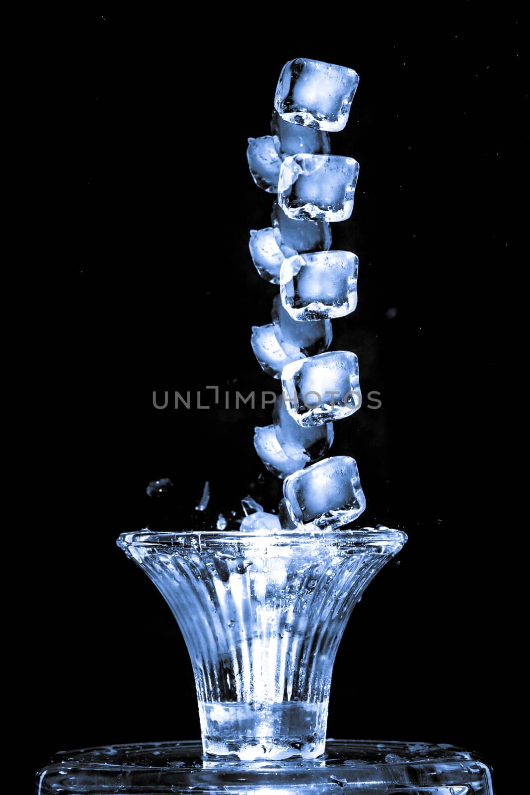 Stroboscopic effect created using flash capturing the motion ice as it splashes into a glass