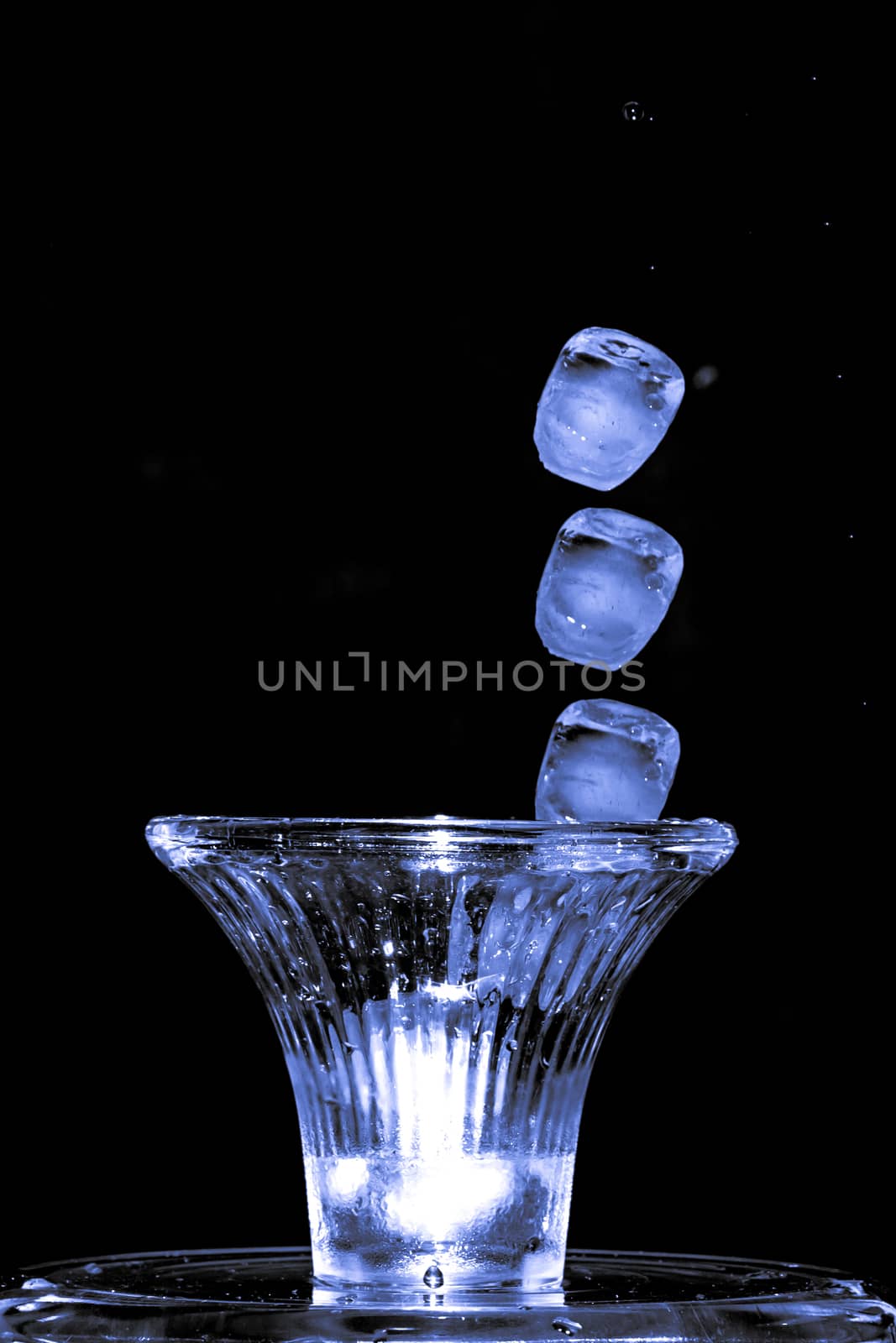 Stroboscopic effect created using flash capturing the motion ice as it splashes into a glass