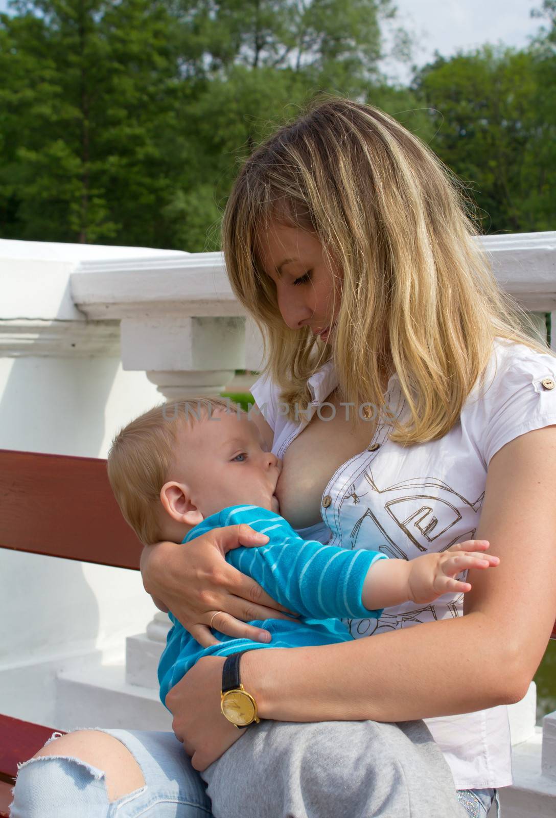 young mother breastfeeding her son in the park