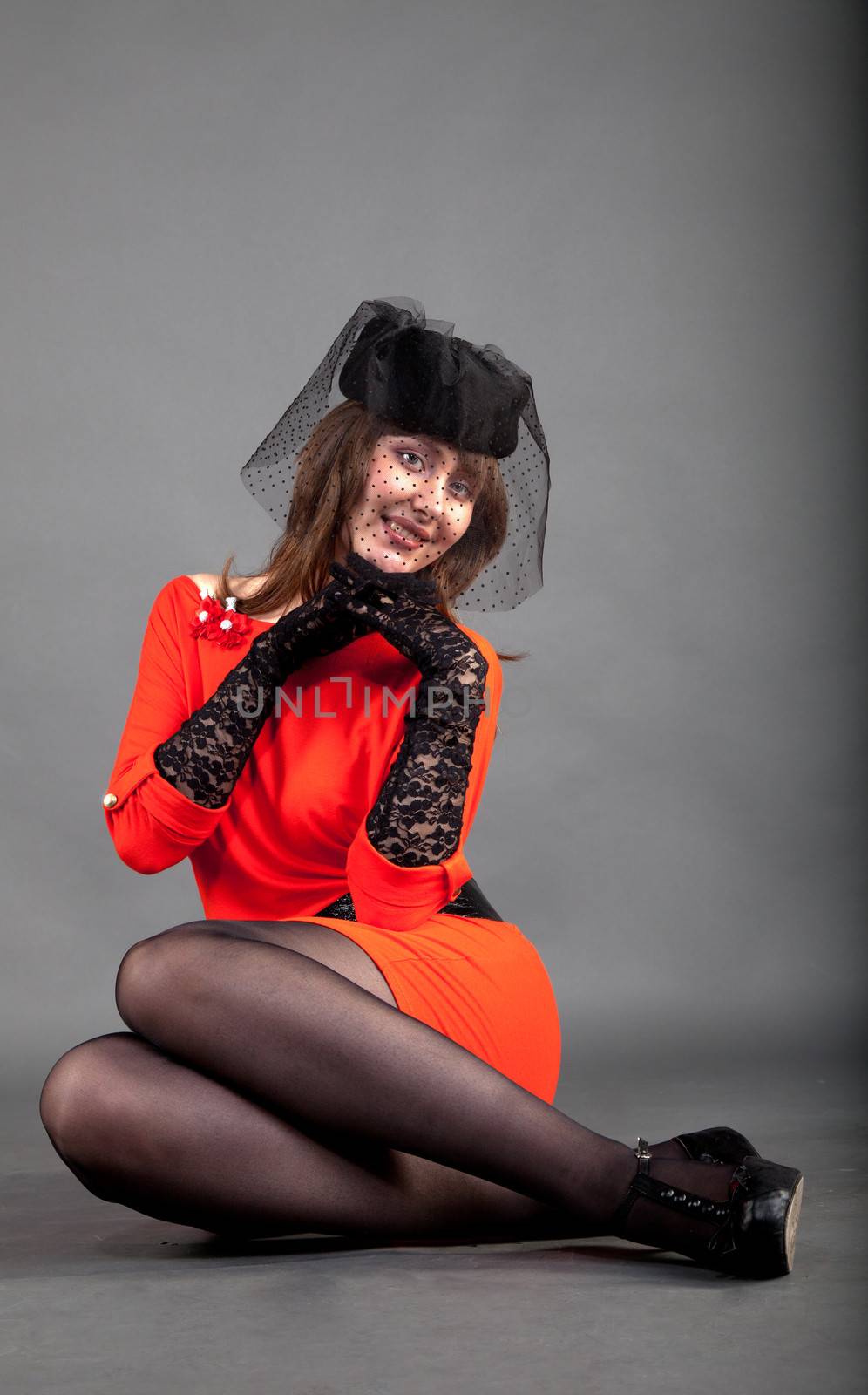 young girl in a red dress and a black hat with a veil sitting on the floor