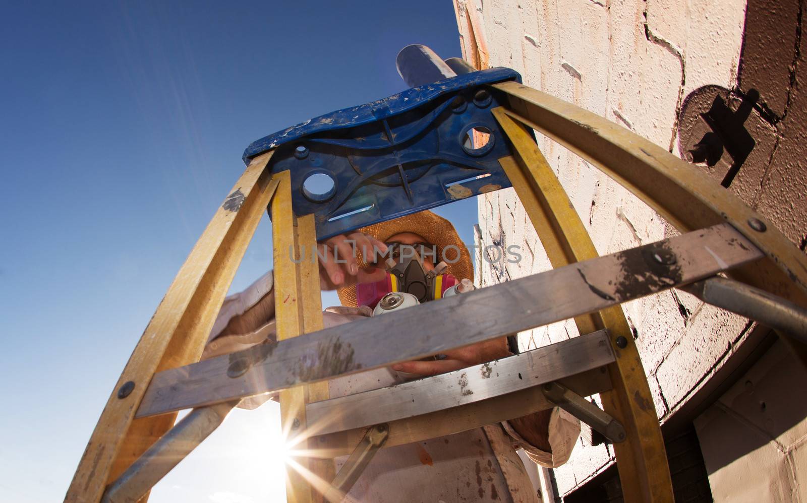 Graffiti artist framed by ladder and working on mural