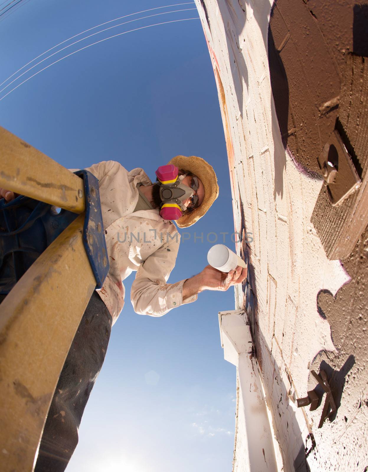 Wide angle view of graffiti artist on ladder making a mural