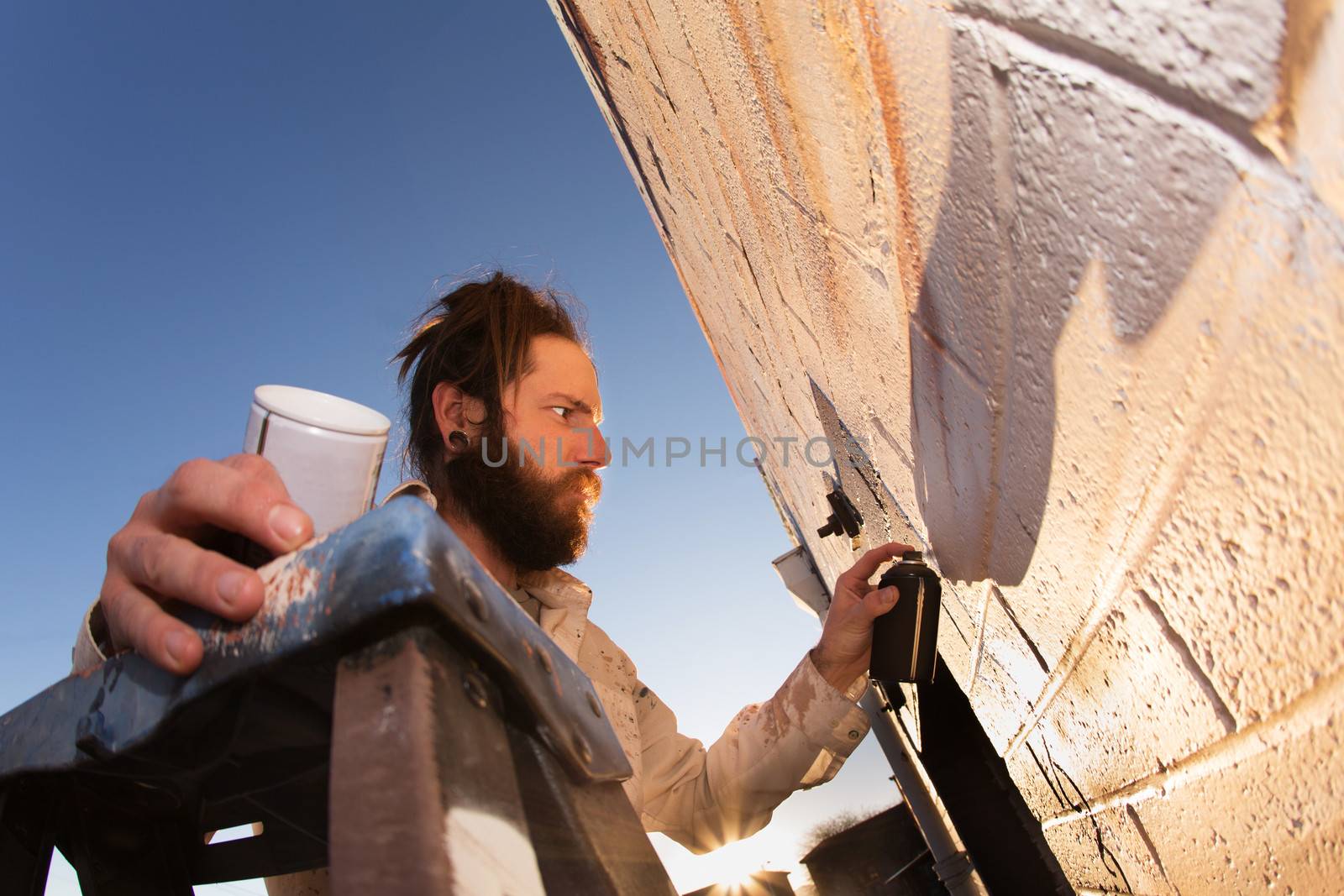 Male graffiti artist creating mural on wall