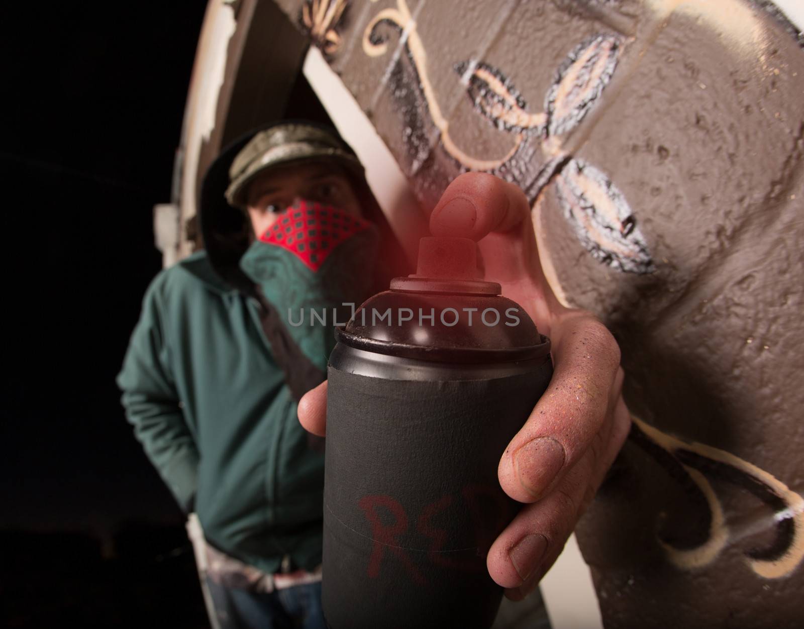 Man with hood and face covering holding spray paint can