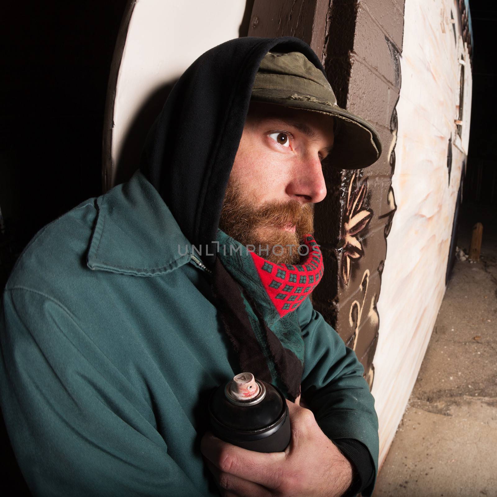 Gang member with spray paint can leaning against wall