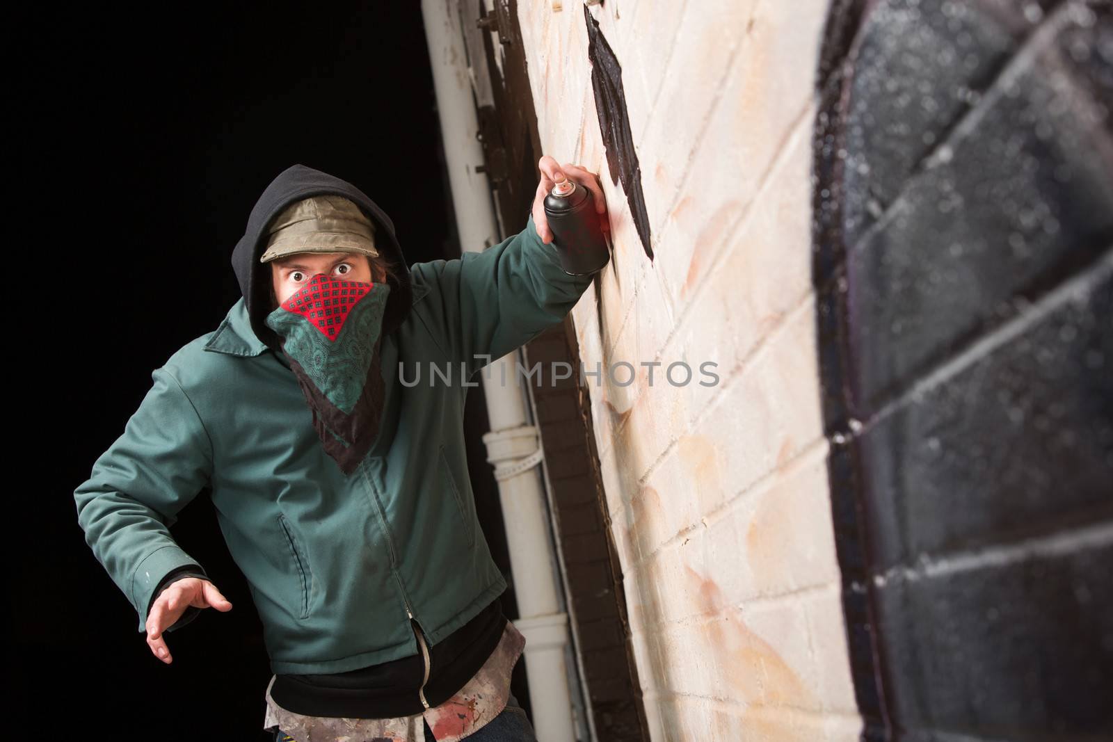 Scared gang member with spray pain can near wall