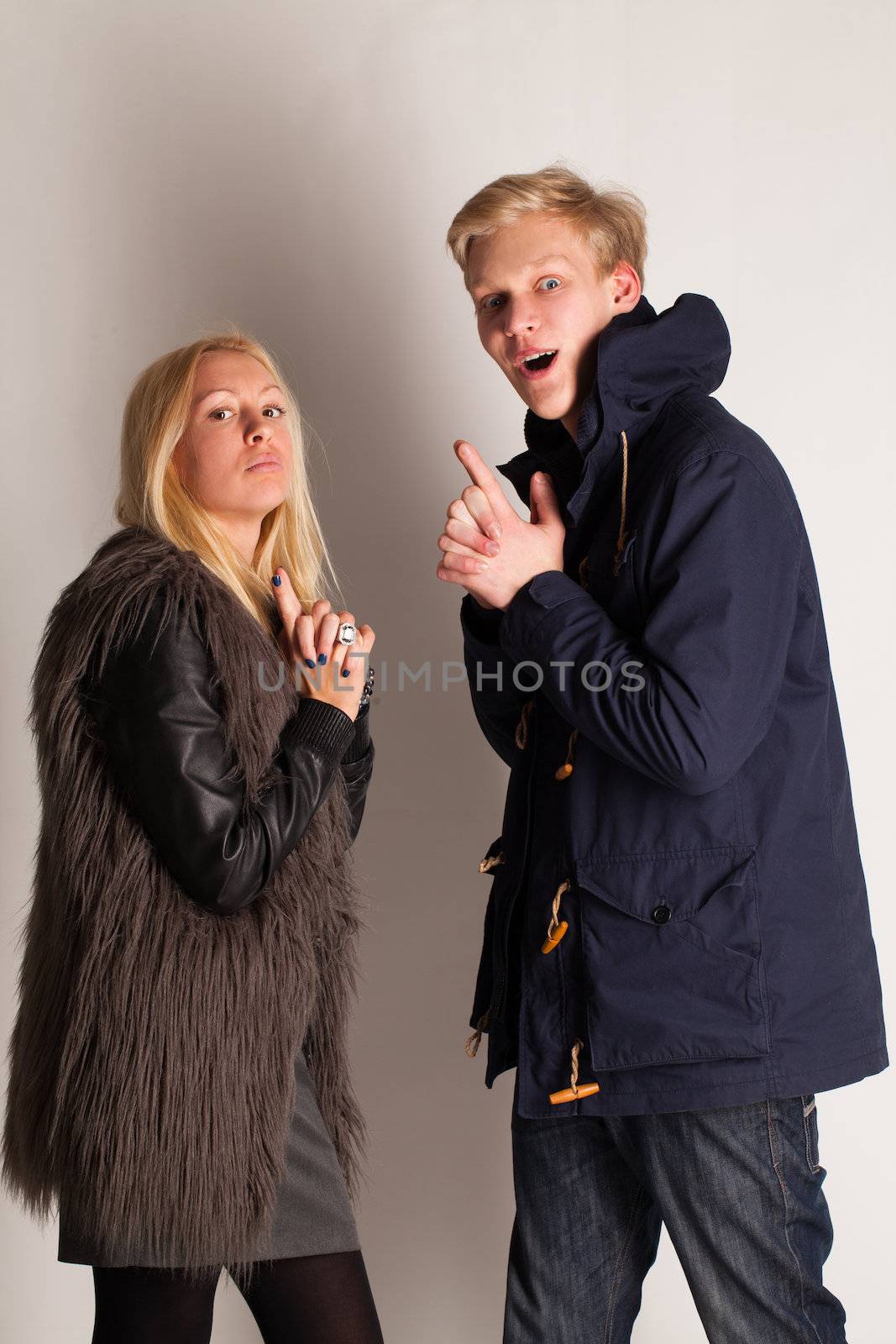 Caucasian blonde couple having fun with fingers up like a guns