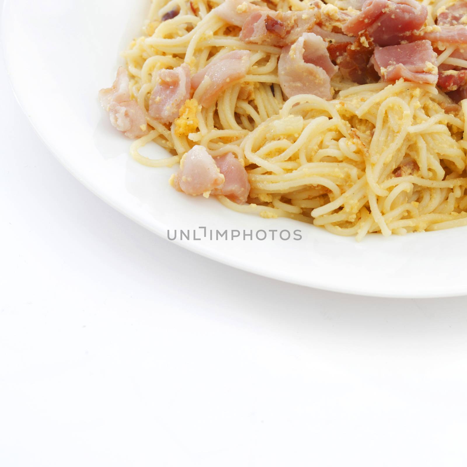 Spaghetti carbonara with fried bacon on white background