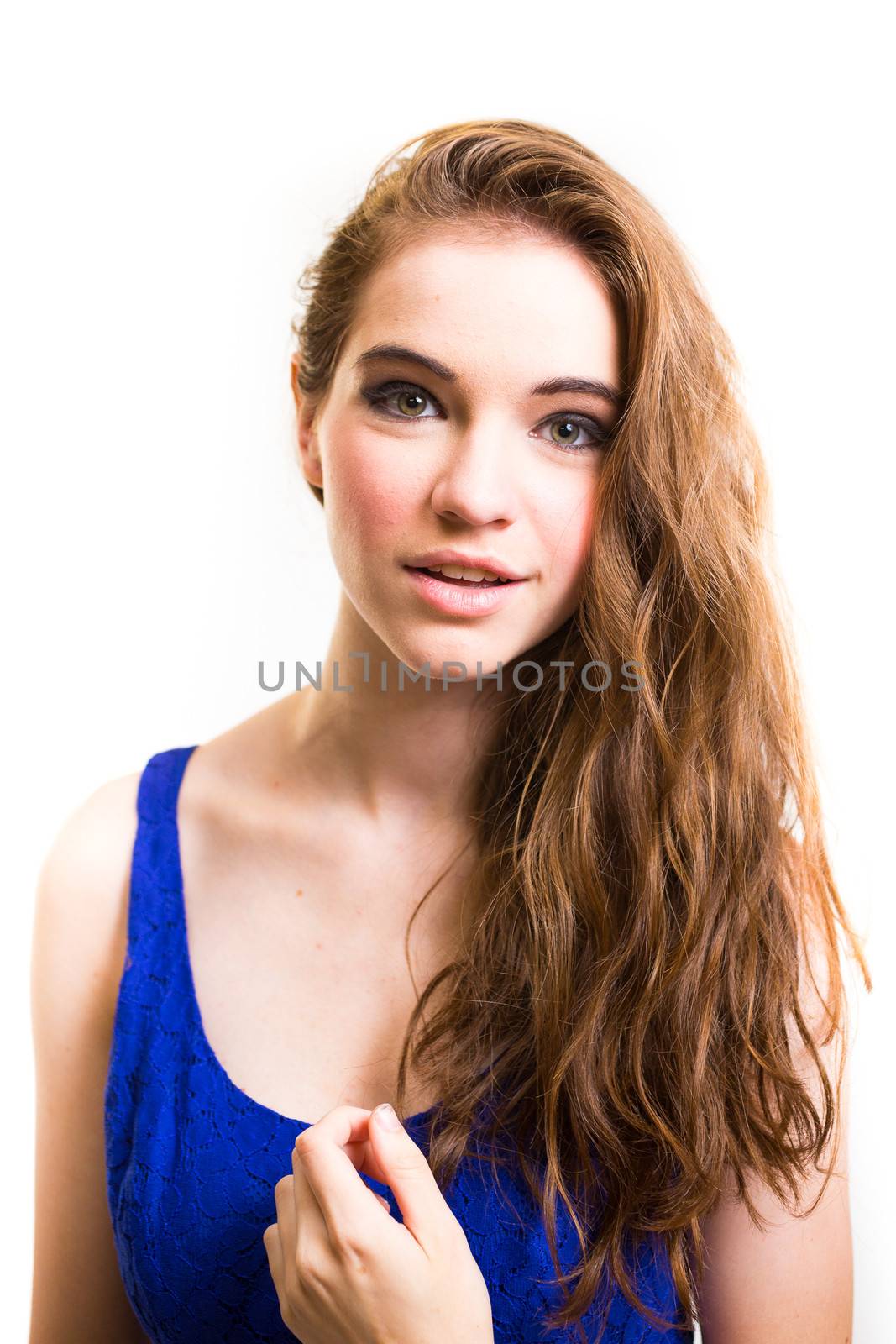 An attractive teen poses for a photo indoors in a lighting studio against a white background with a fashion style feel to the image.