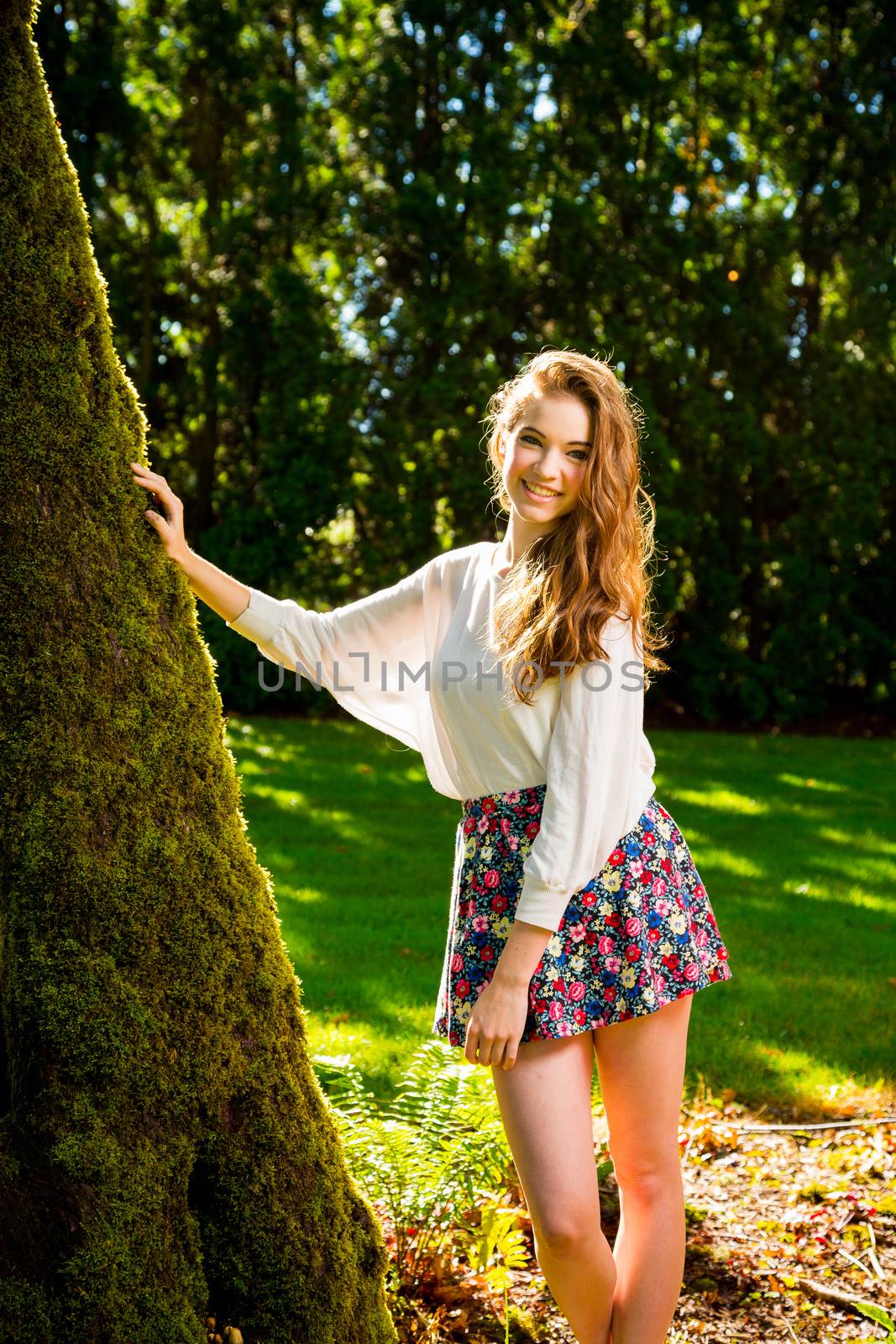 A beautiful young girl poses for a fashion style portrait outdoors at a park with natural lighting.