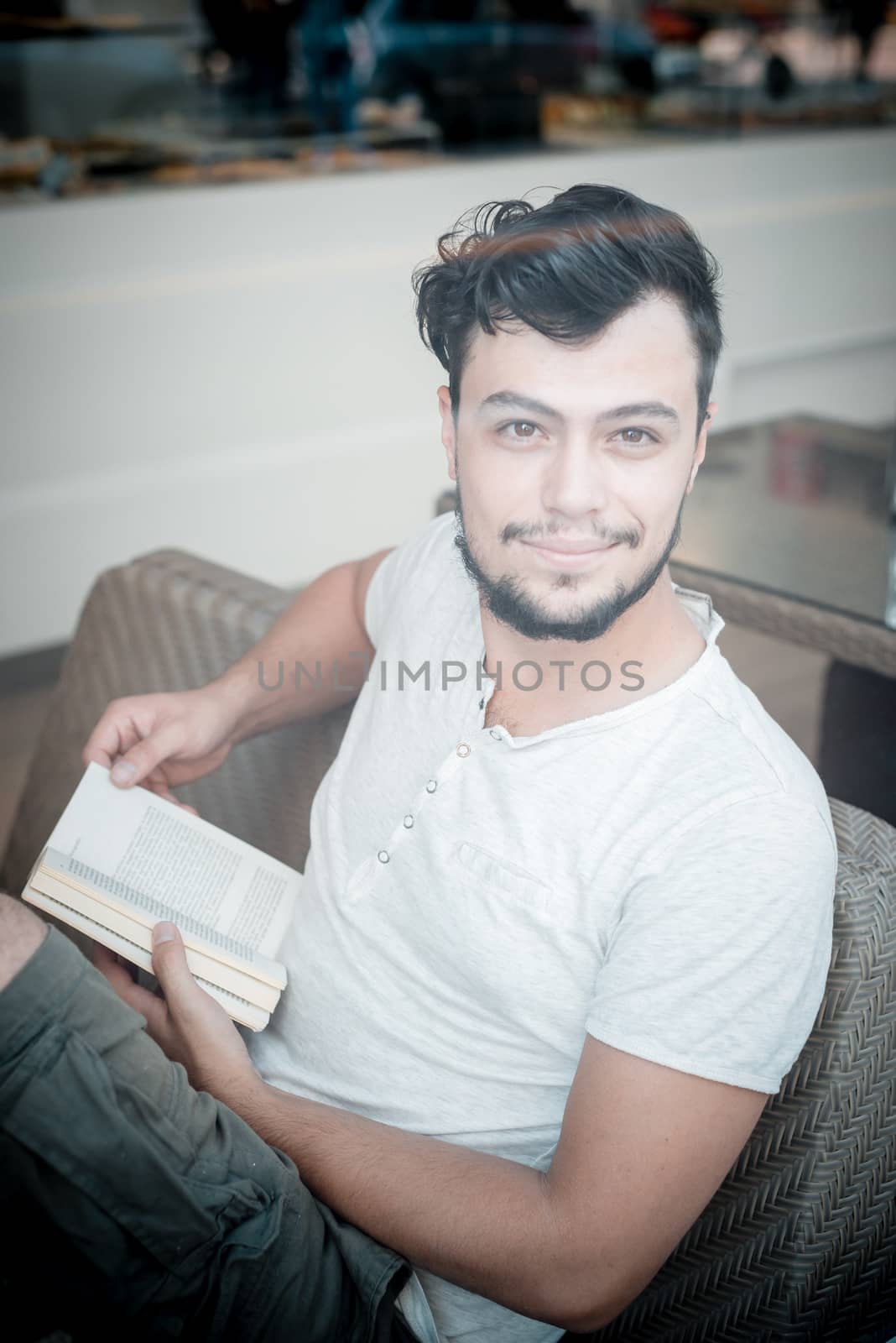young  stylish man reading book in a bar