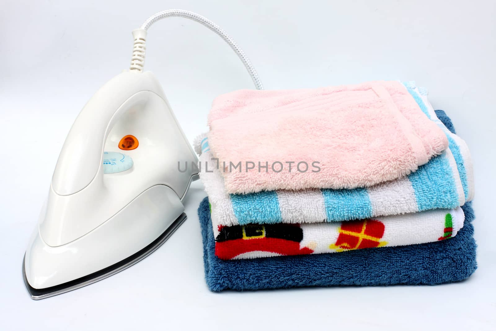 Pile of colorful clothes and electric iron on white background