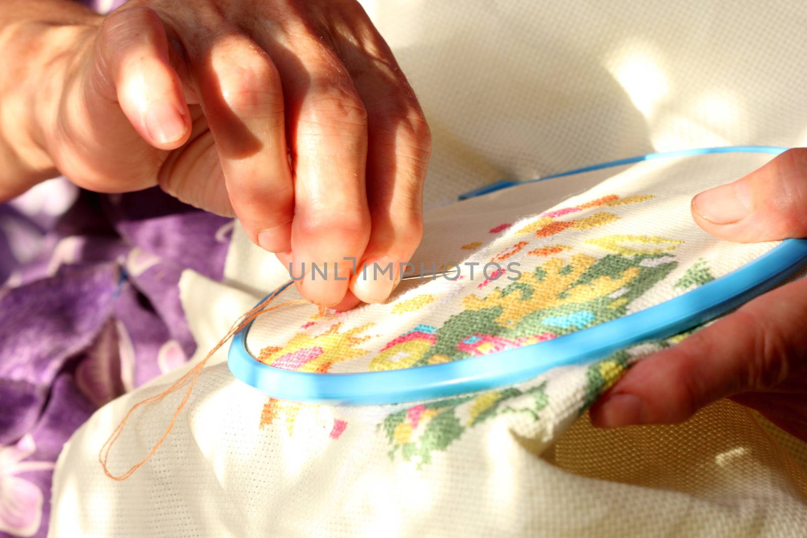 Hands of an old woman busy embroidering
