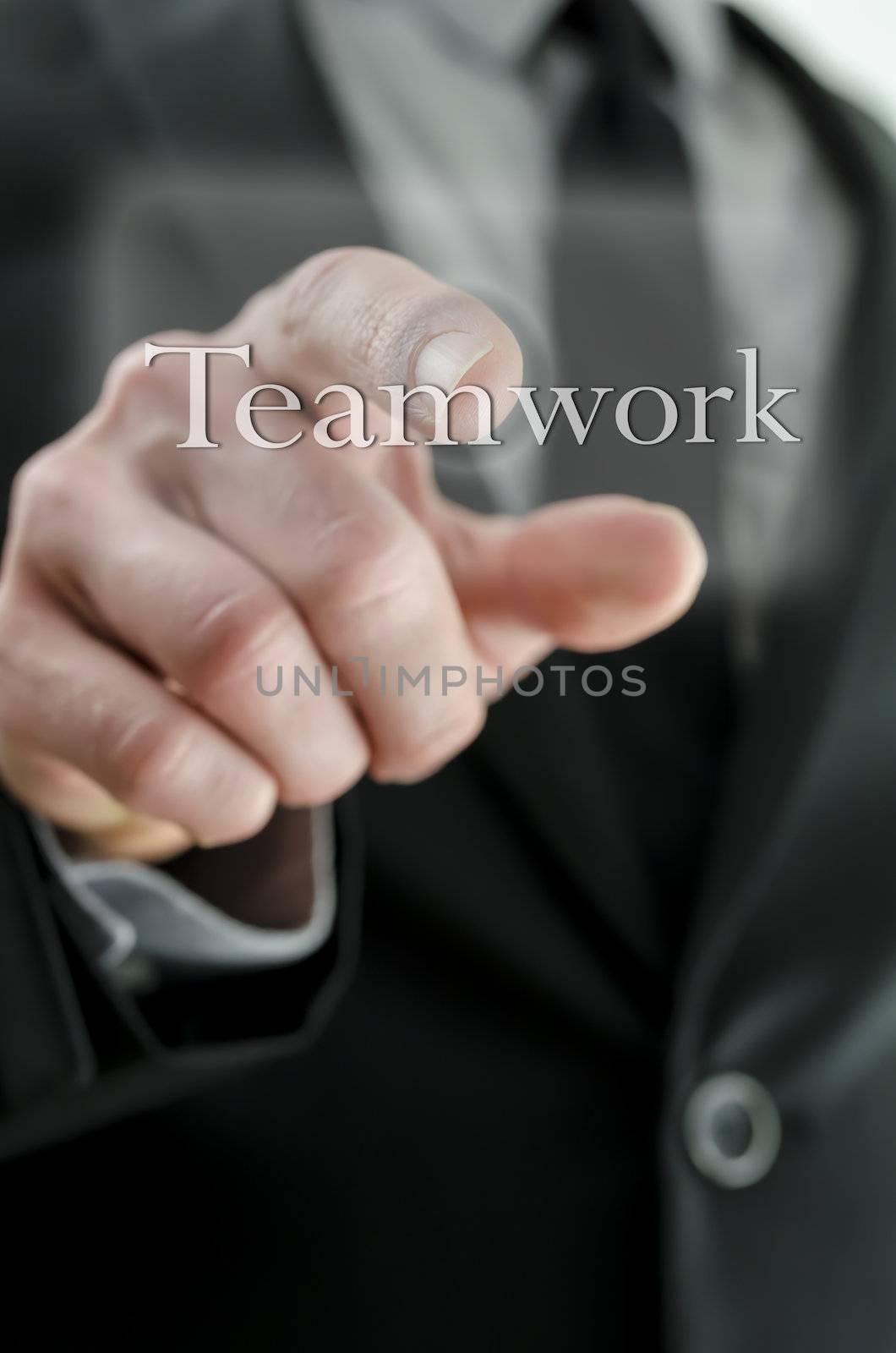 Closeup of businessman hand pressing Teamwork icon on a virtual screen.