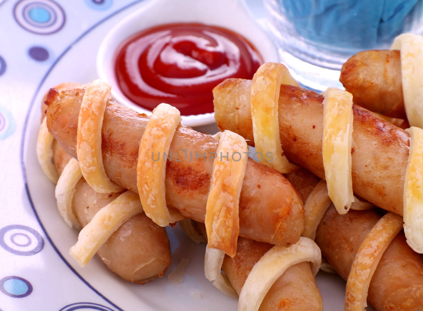 Fresh baked twisted pastry around chicken sausages with ketchup.