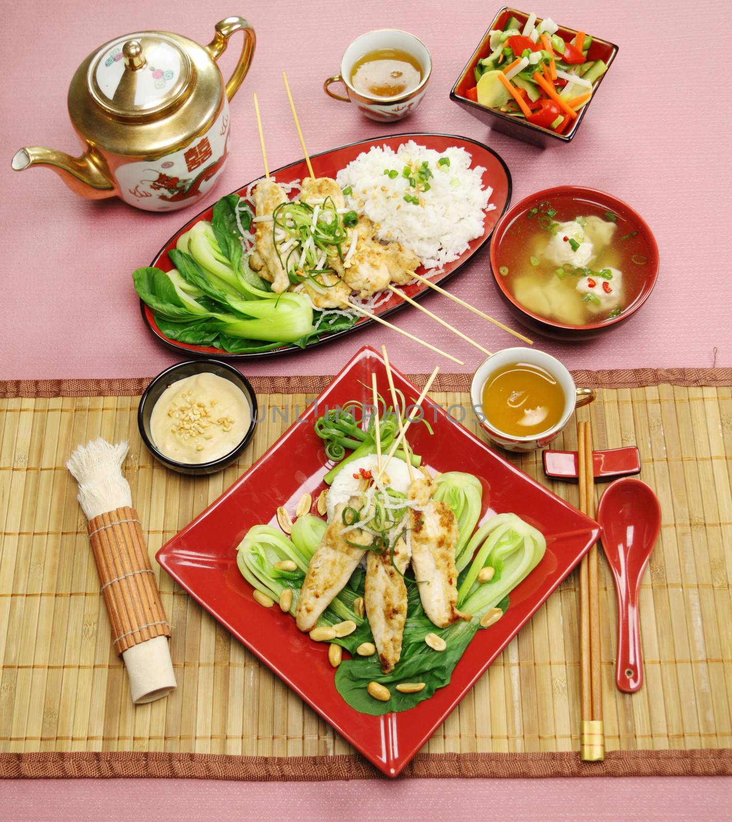Full table setting of Asian chicken skewers with short soup and vegetables.