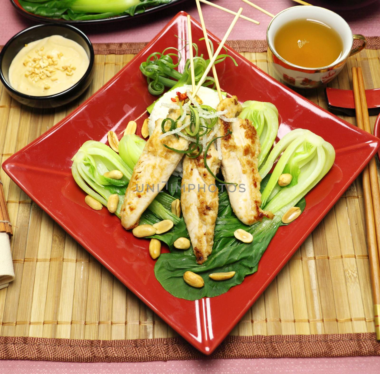 Asian chicken skewers on a bed of Chinese vegetables ready to serve.