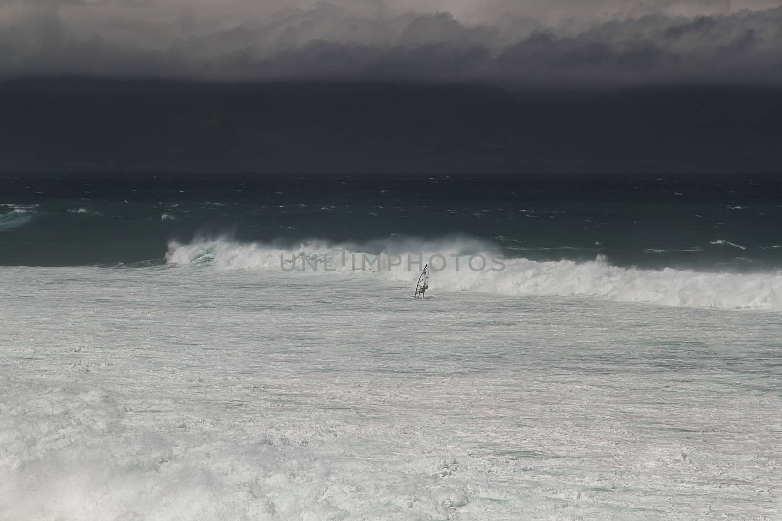 Windsurfer in the distance surfing away from a storm surge