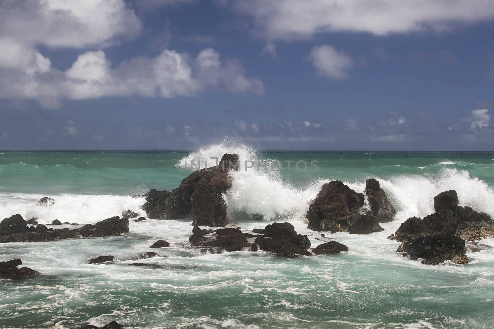 volcanic rock formation being pounded by wave