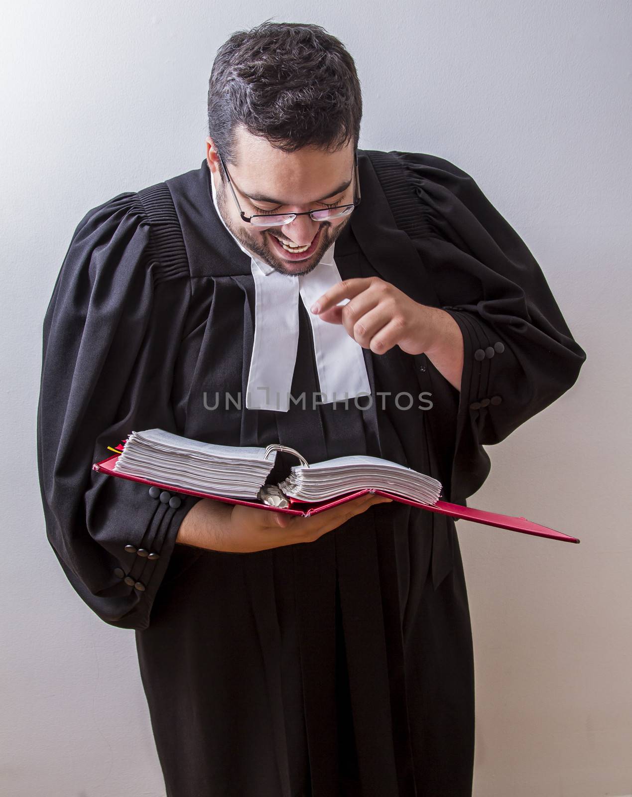 Man in canadian lawyer toga holding a book of law laughing at it