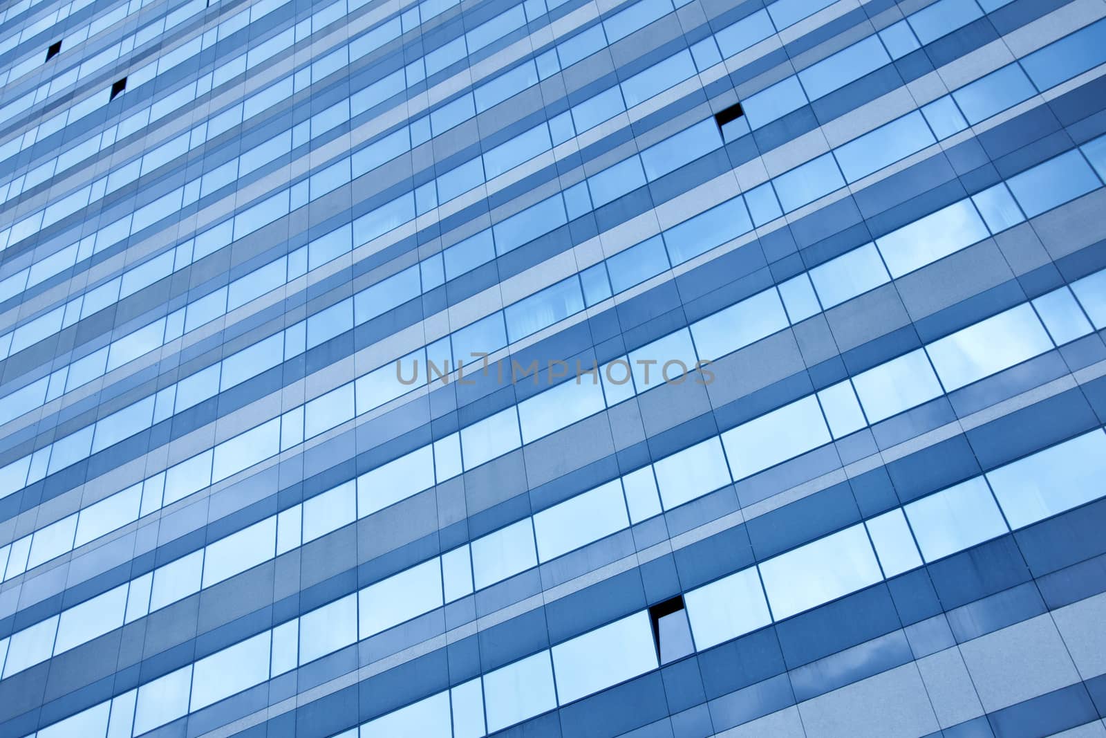 modern blue  facade reflecting blue sky with some open windows 