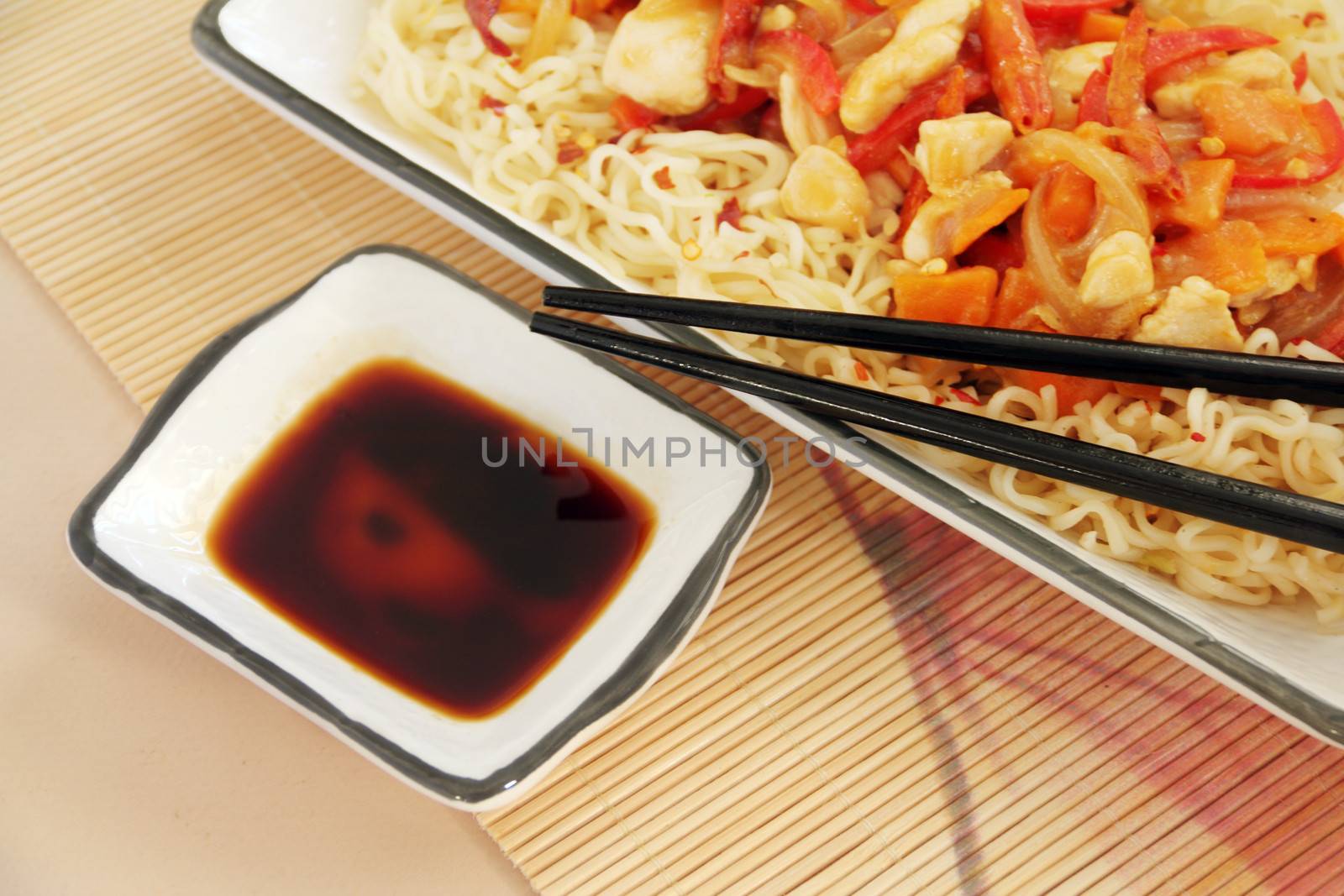 Condiment of soy sauce with chopsticks and chilli chicken.