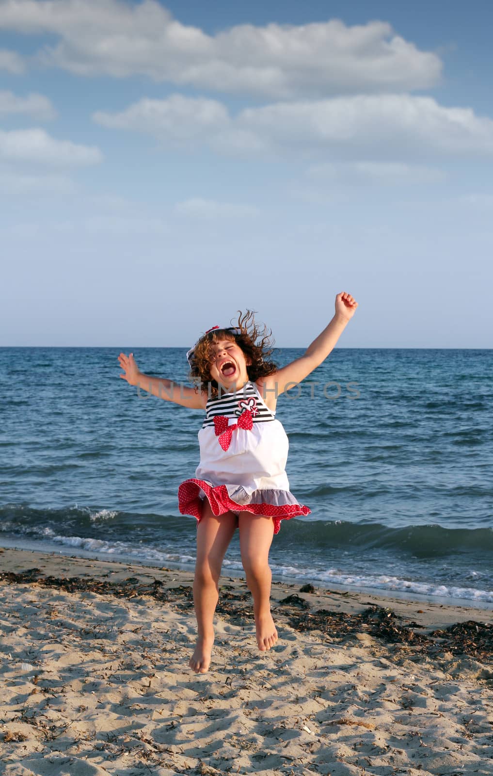 happy little girl jumping on the beach by goce