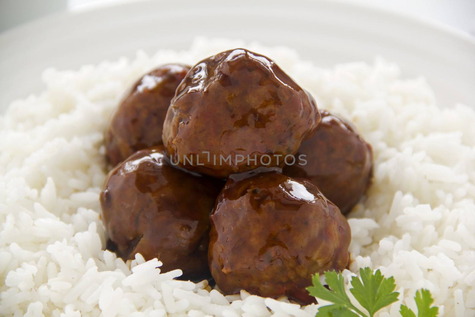 Chinese meat balls in hoisin sauce on a bed of white rice with parsley.