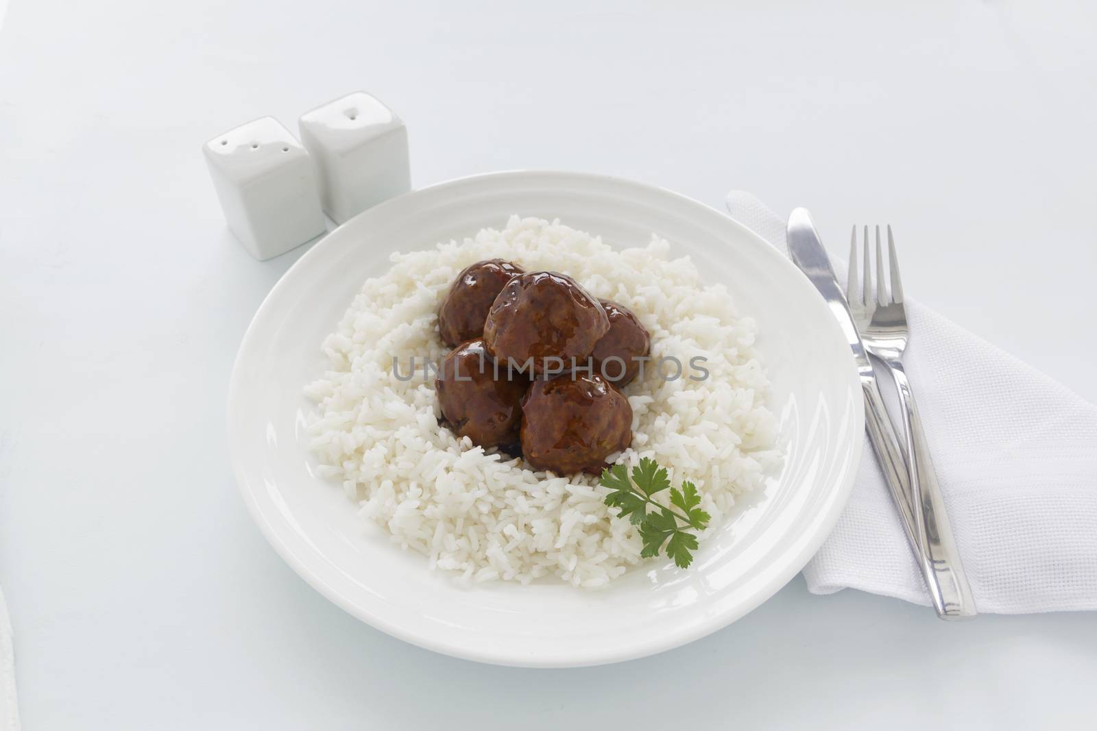 Chinese meat balls in hoisin sauce on a bed of white rice with parsley.