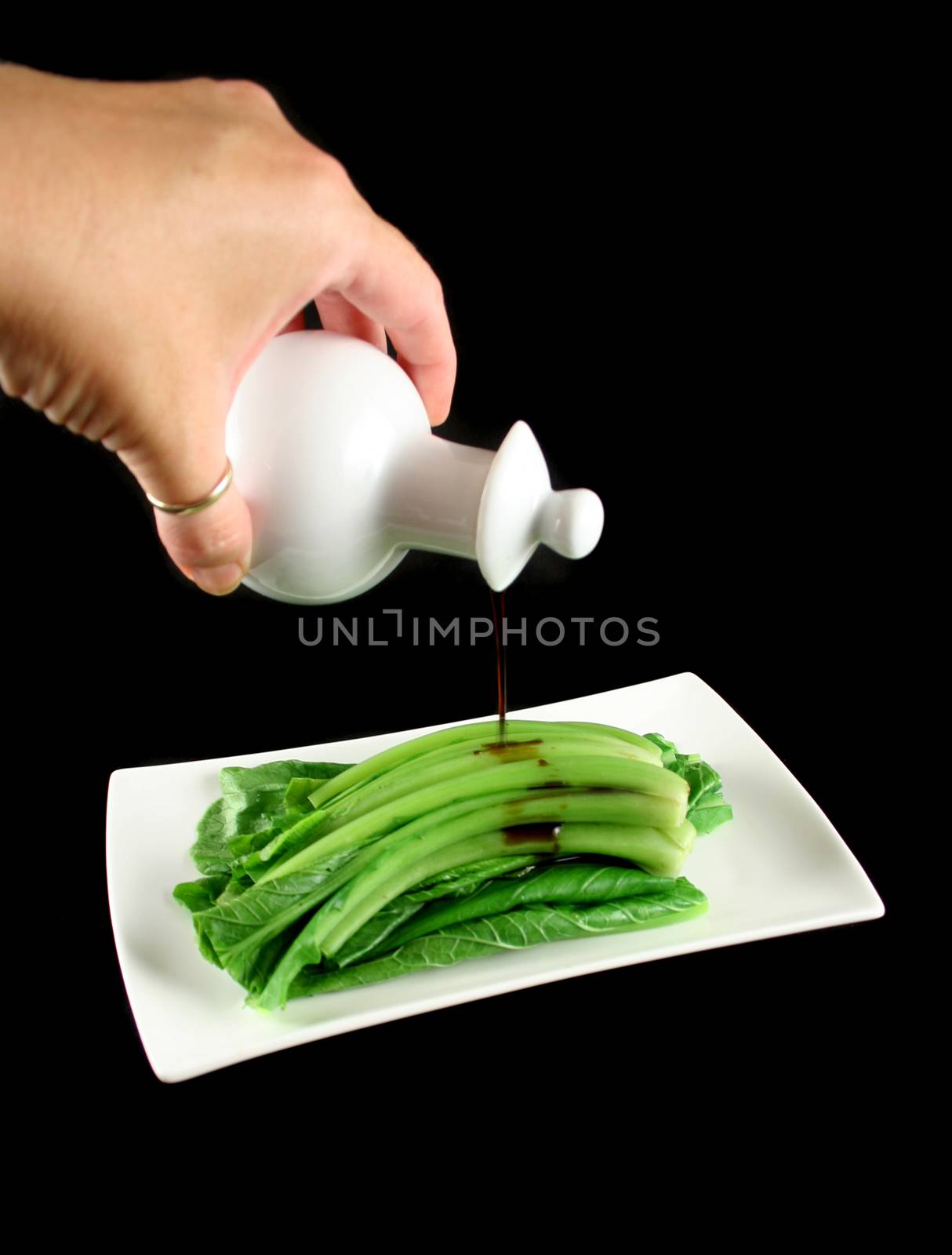 Soy sauce being poured on the Asian vegetable Choy Sum.