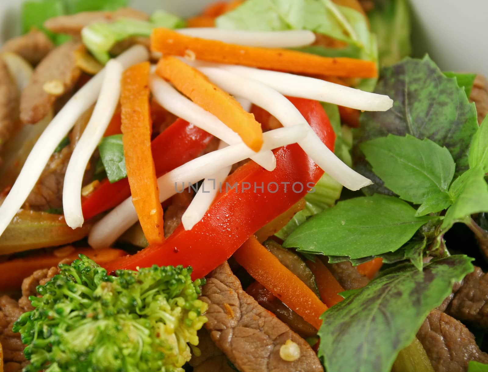 Stirfry beef and vegtables with a purple green basil garnish.