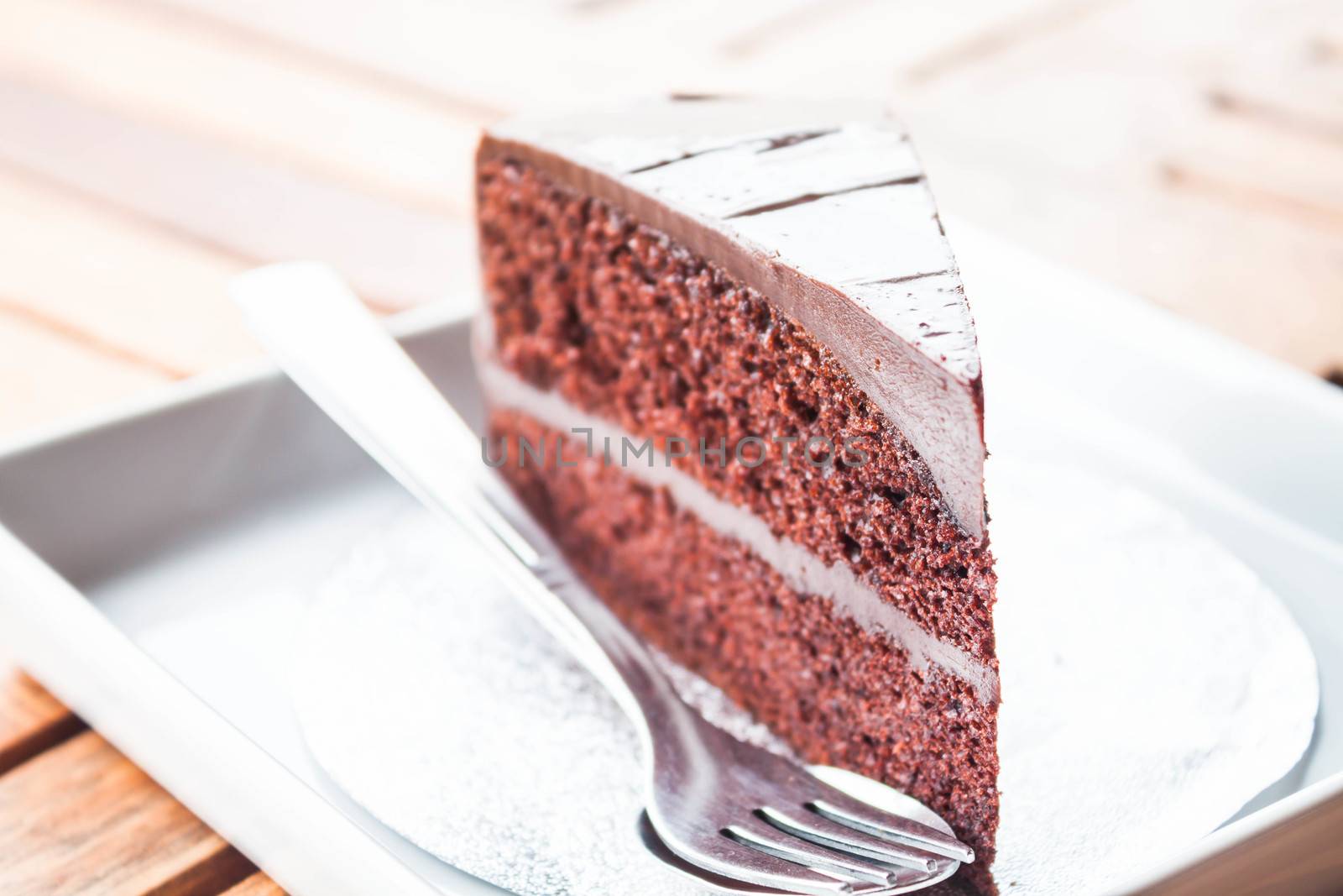 Chocolate cake serving on white dish with spoon and fork by punsayaporn