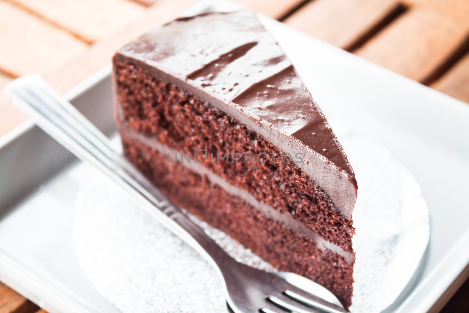 Chocolate cake serving on white plate with spoon and fork