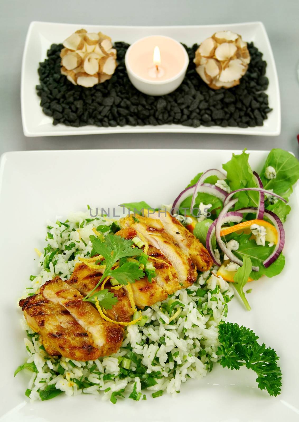 Table setting of chicken tikka on a bed of lemon coriander rice with salad.