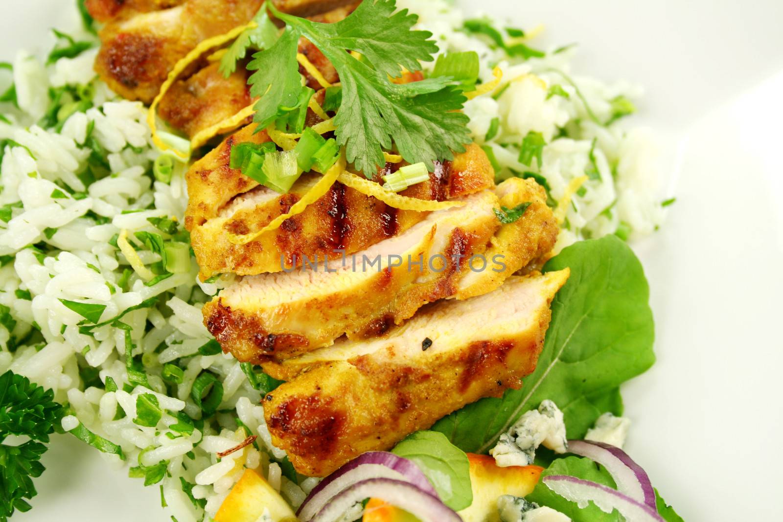 Table setting of chicken tikka on a bed of lemon coriander rice with salad.