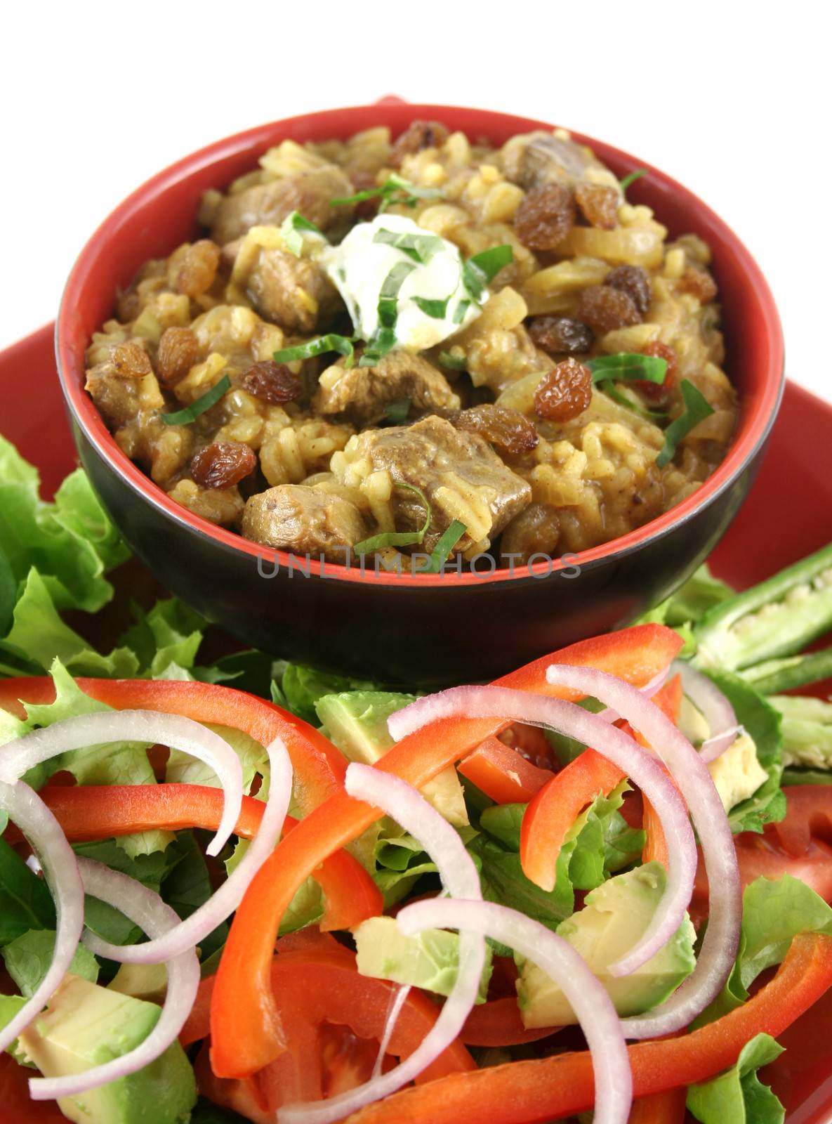 Indian lamb biryani with sultanas and yoghurt and a side salad.