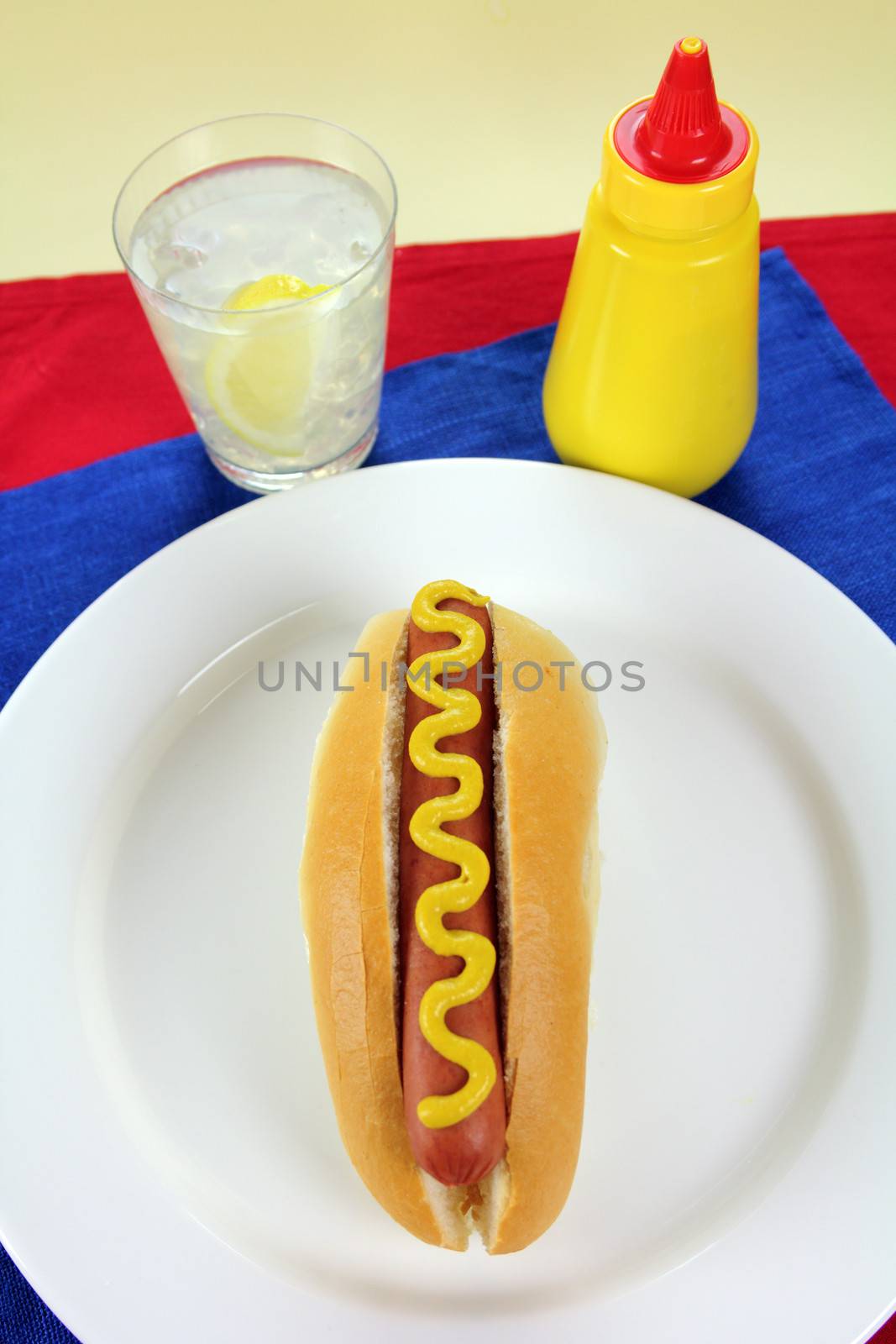 American hot dog with mustard on red and blue napkins.