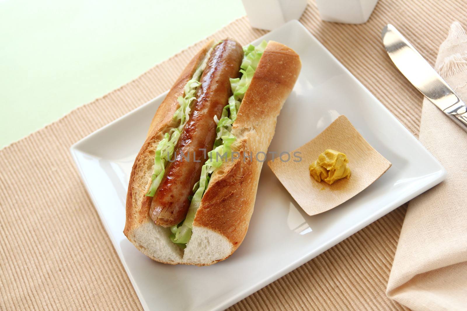 Delicious hot dog with a fried pork sausage with cabbage and hot mustard.