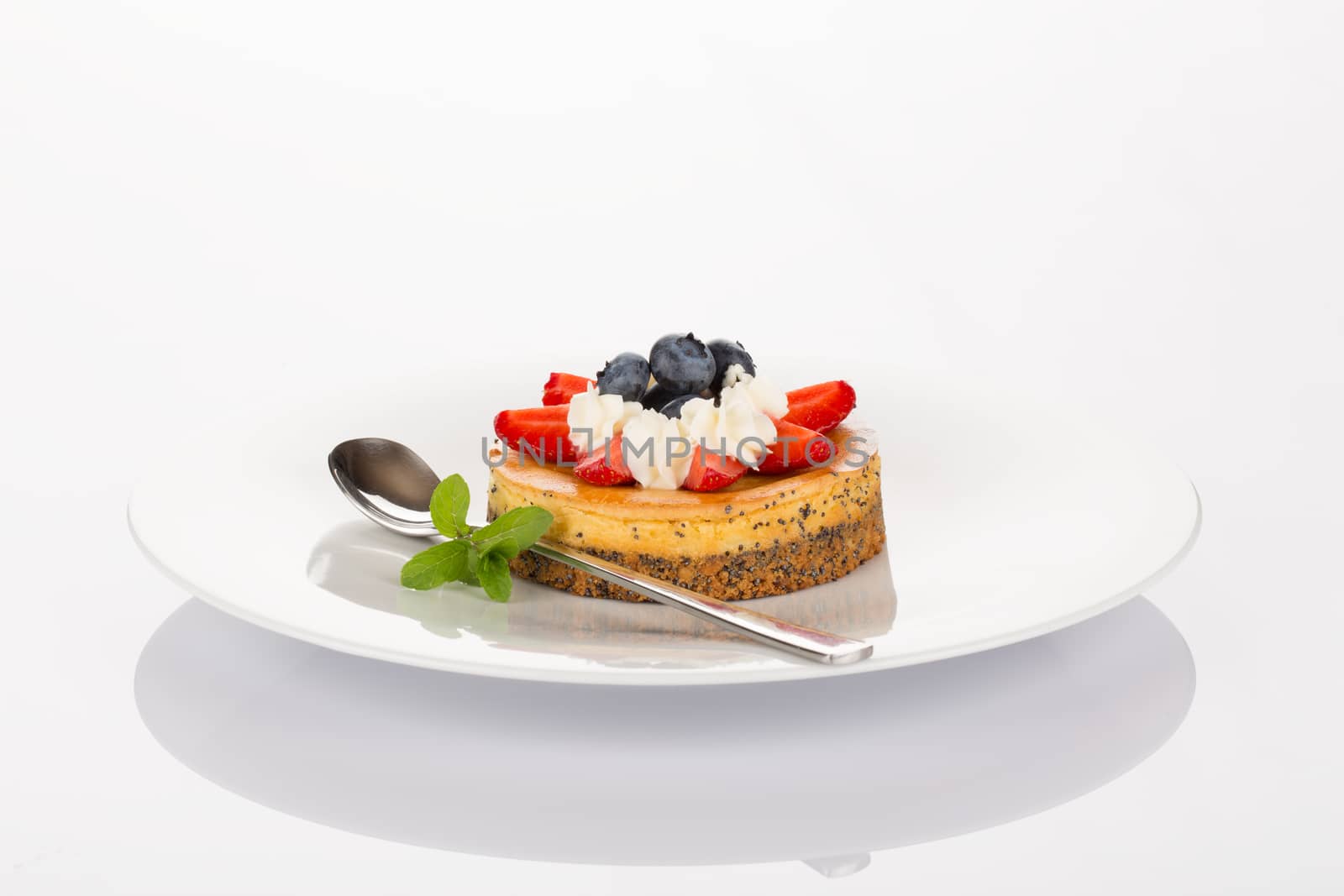 Cheese-cake with strawberry, blueberry, mint and cream on white plate.