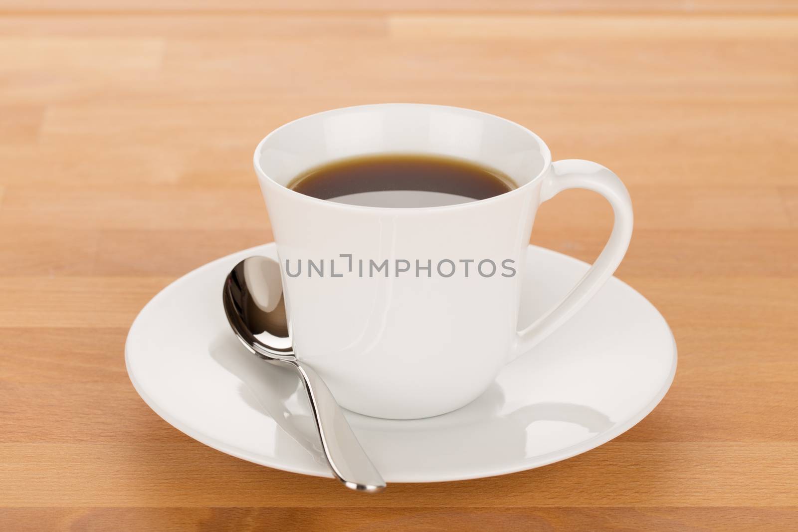 Cup of coffee and silver spoon on wooden table close up.