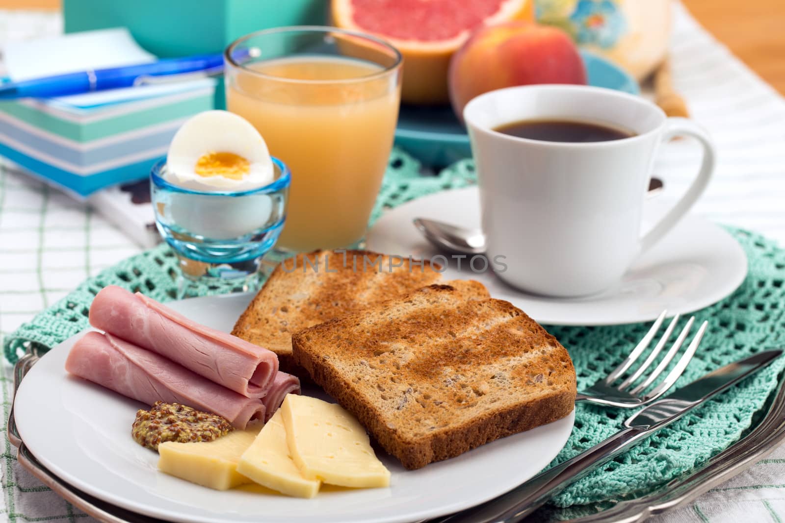 Breakfast with toast, ham, cheese, egg, grapefruit, juice and cup of coffee.