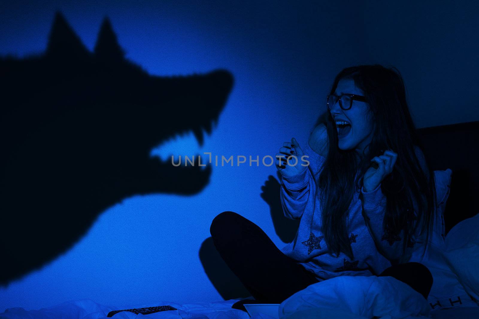 Beautiful girl frightened from wolf shadow at wall in bedroom