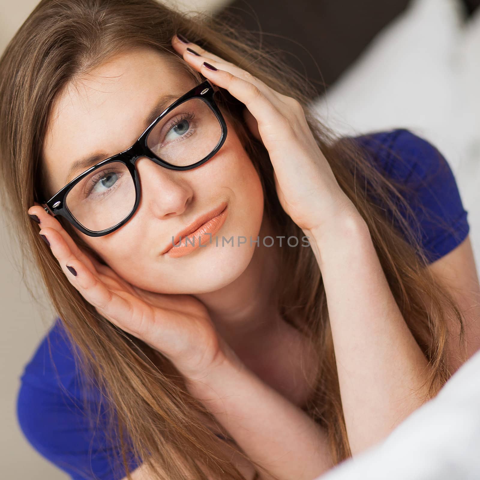 Cute young girl in glasses posing on the bed