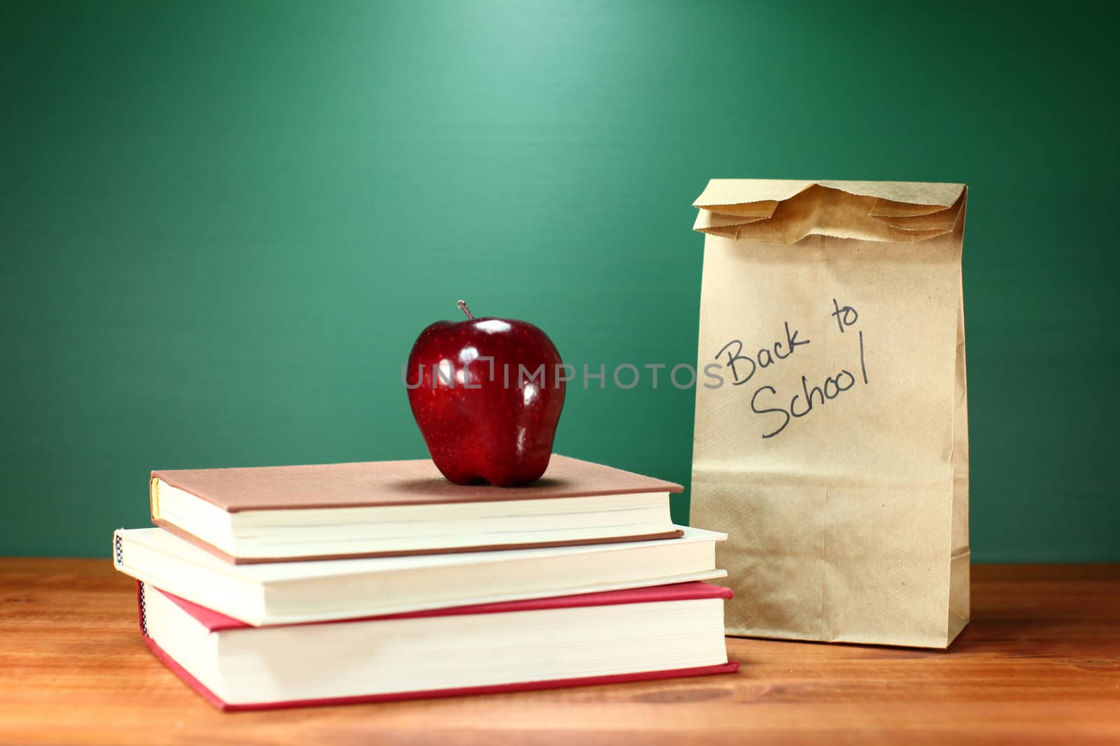 Books, Apple and Lunch on Teacher Desk by tobkatrina