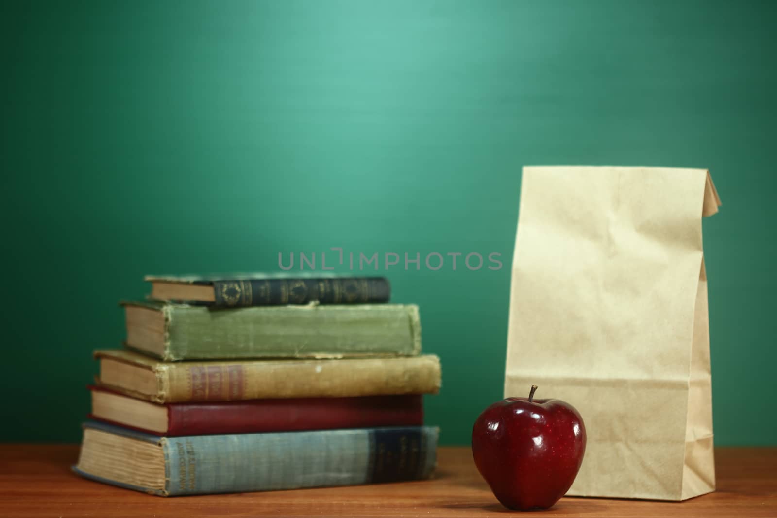 Books, Apple and Lunch on Teacher Desk by tobkatrina