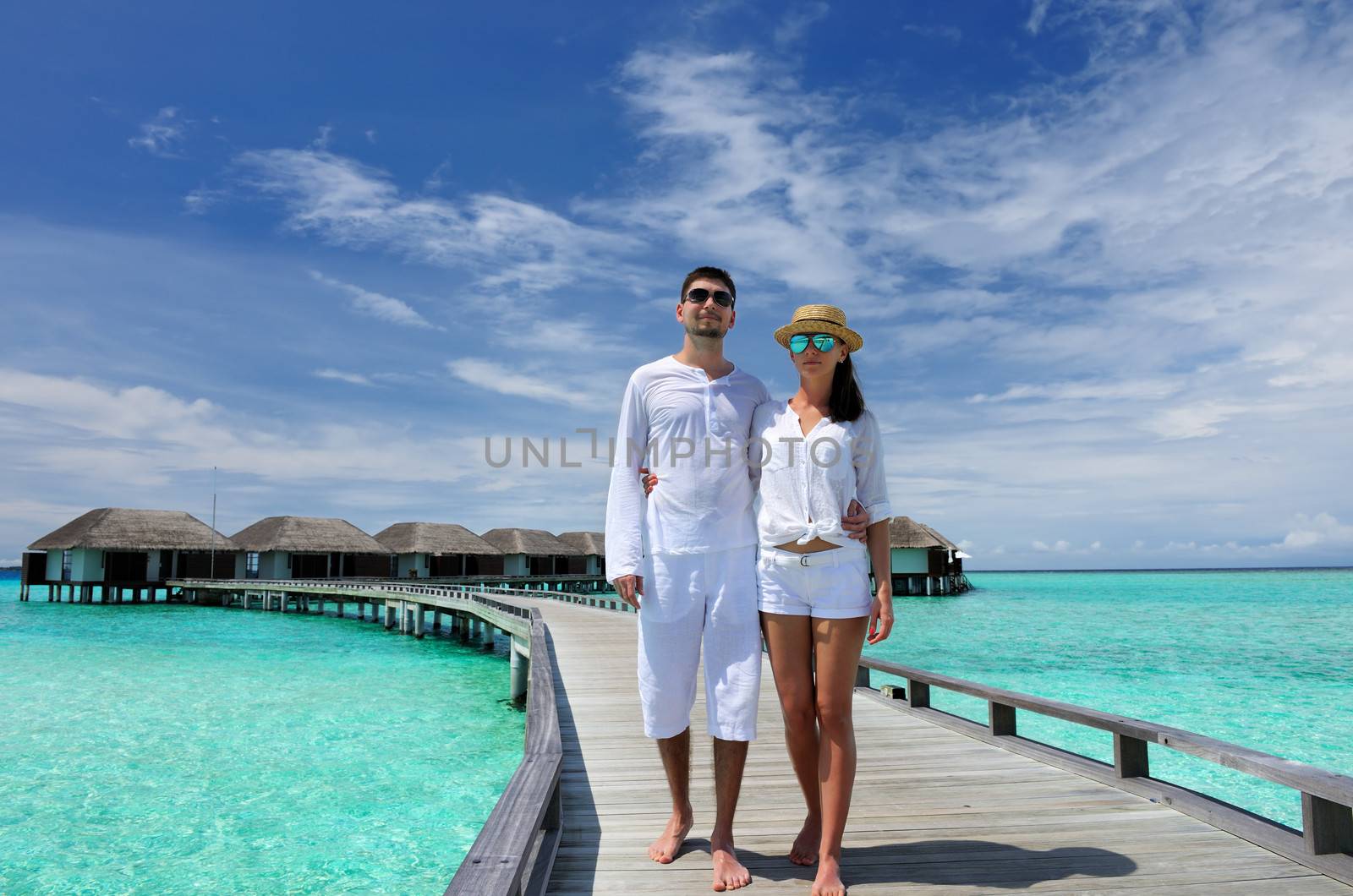 Couple on a tropical beach jetty at Maldives